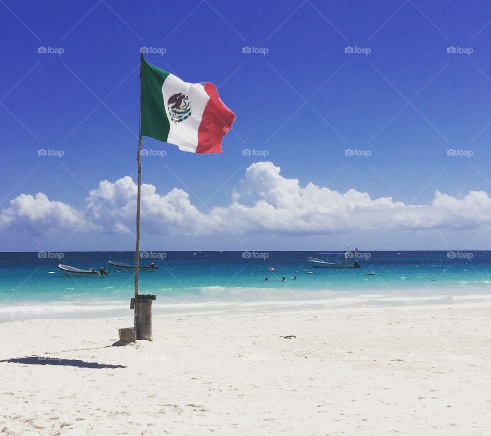 Mexican flag waving at tourist on this beach in Tulum Mexico
