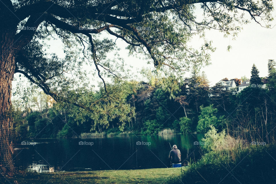 A man fishing by himself in a park