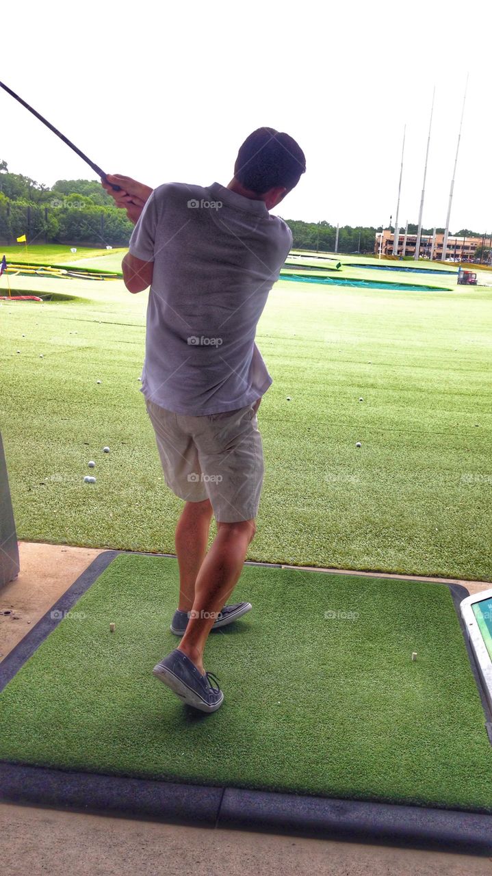 Golf pro. Man hitting a golf ball at Top Golf