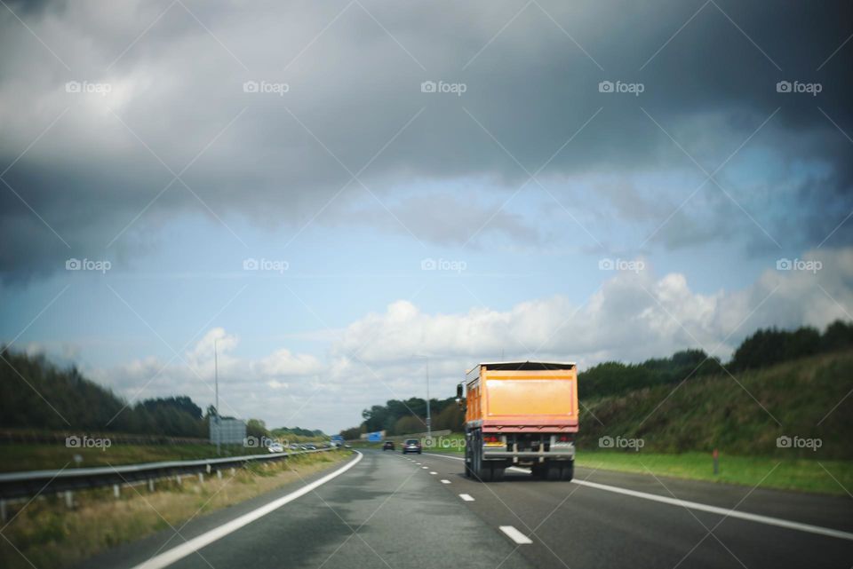 Truck, yellow color on the road. North of The Netherlands, picture taken from the car.