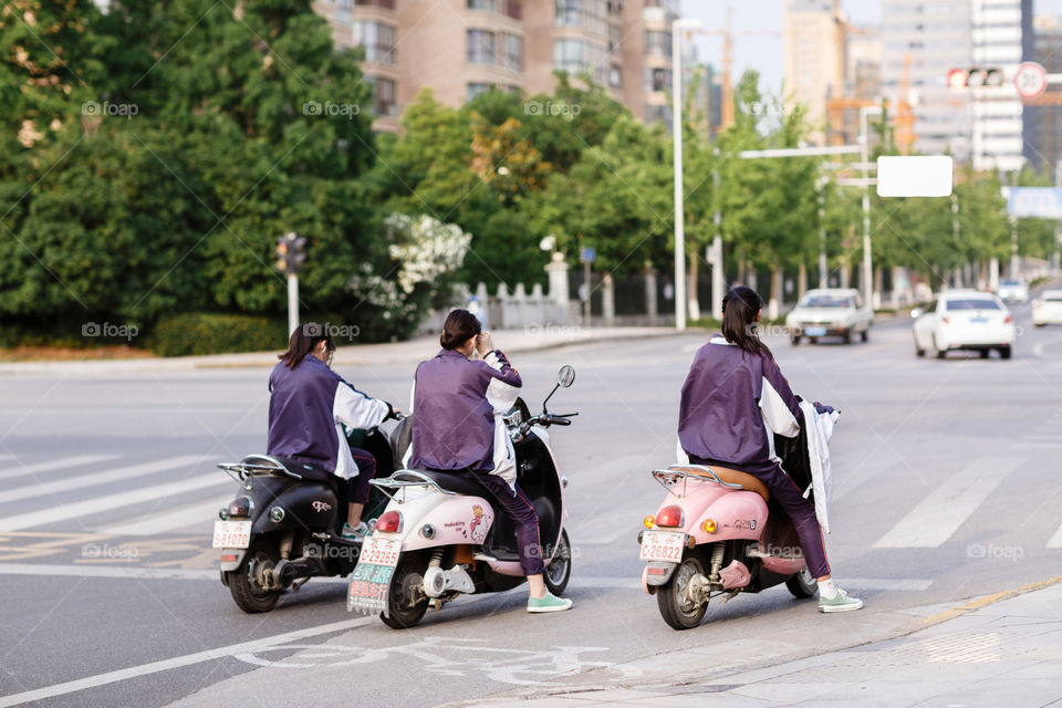 Girls riding on scooters on pedestrian 