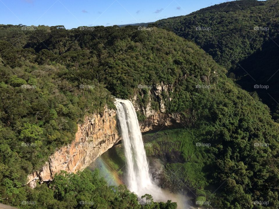 Waterfall on a green view and a rainbow below it