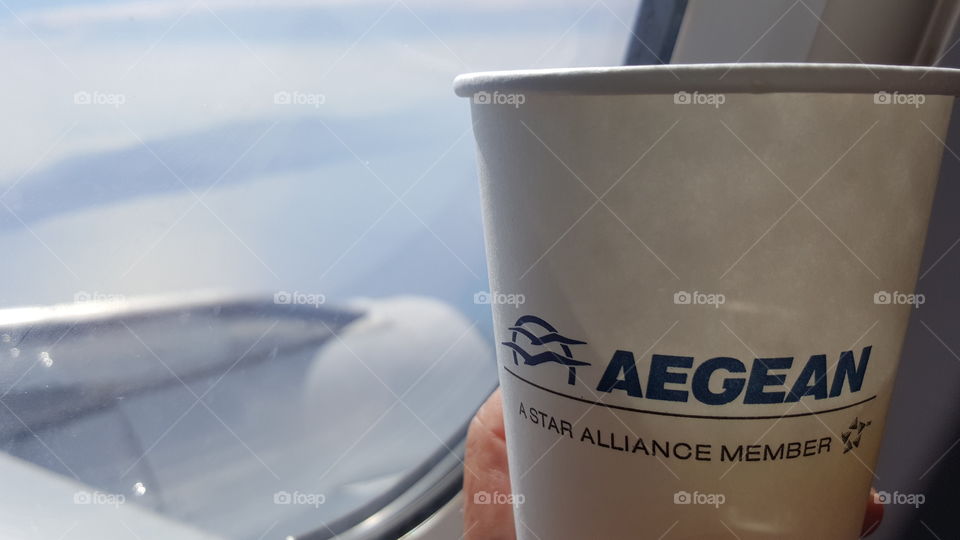 Flying over the Greek islands. Raising a cup above the Aegean sea with a Star Alliance member Aegean airlines Airbus A320 heading for island vacations.