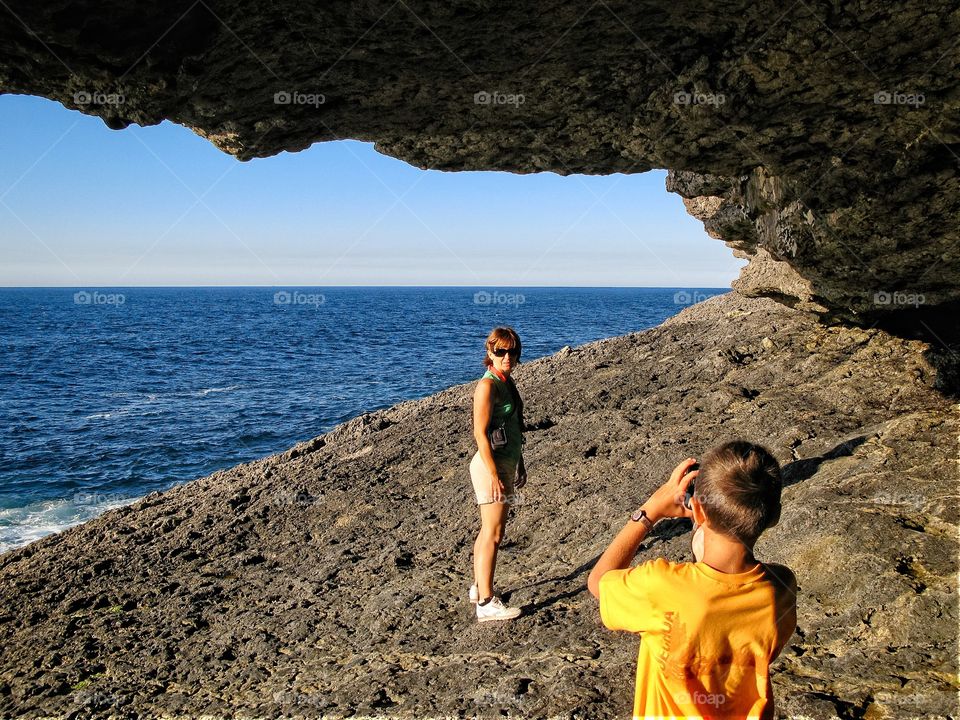 A boy photographing his mum close to the sea 