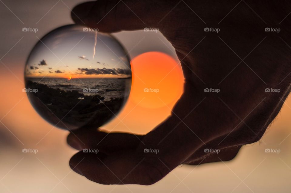 A person holding crystal ball during sunset