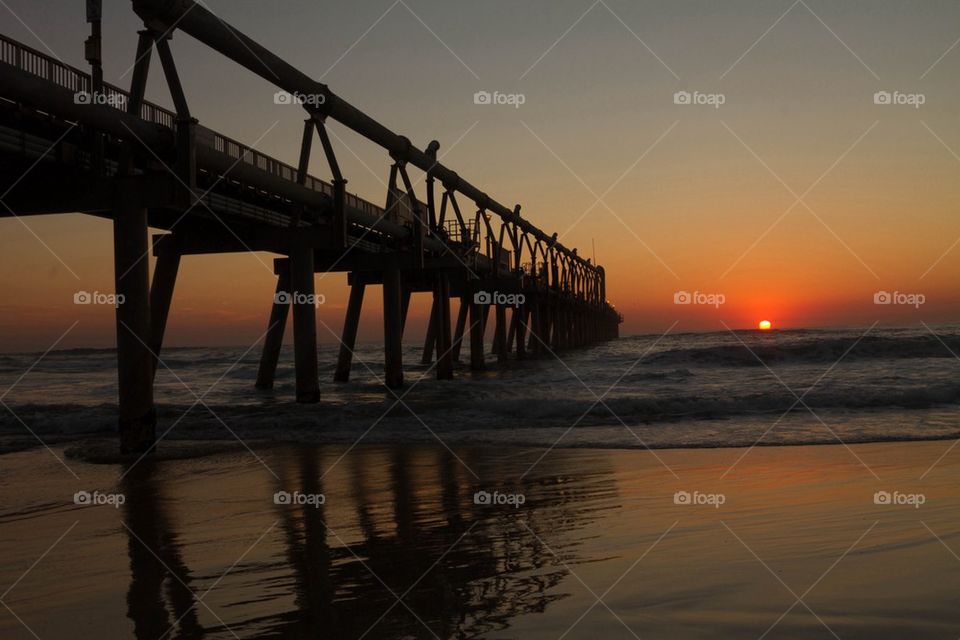 Silhouette of pier at beach during sunset