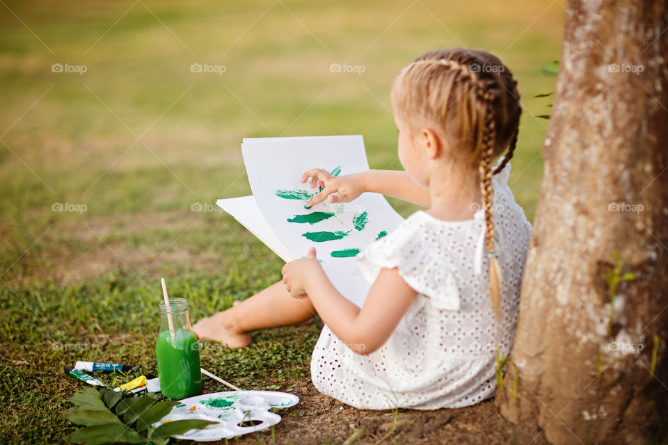 Little girl with blonde hair painting outdoor 