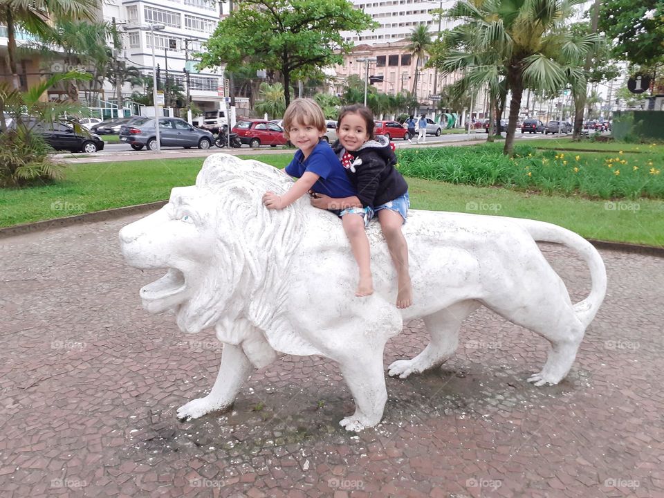 children went for a walk and climbed on the lion statue