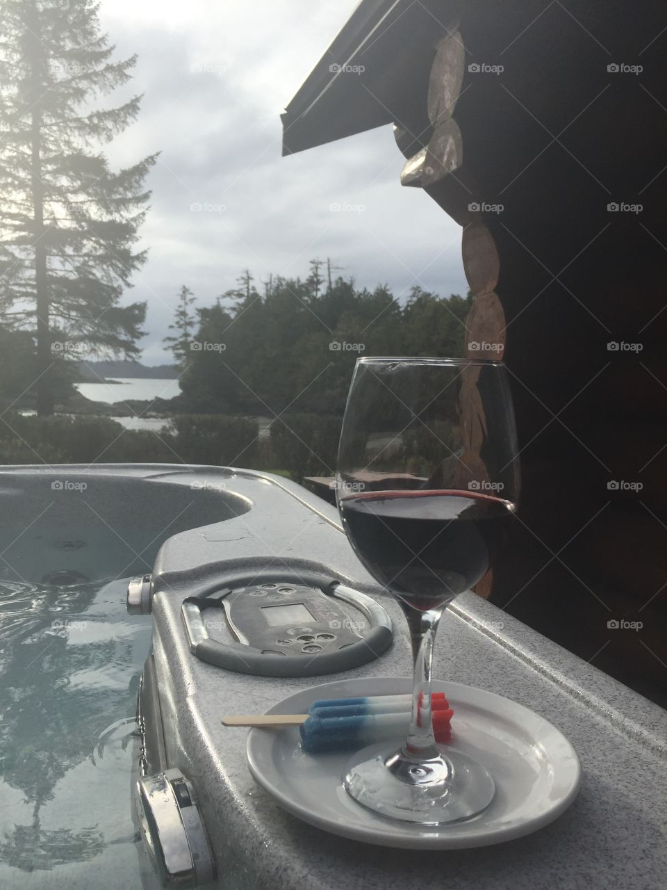 Sitting in an outdoor hot tub enjoying a view of the coastline, ocean, secluded inlet, windswept trees, all while enjoying the perfect pairing of a glass of red wine with a popsicle!