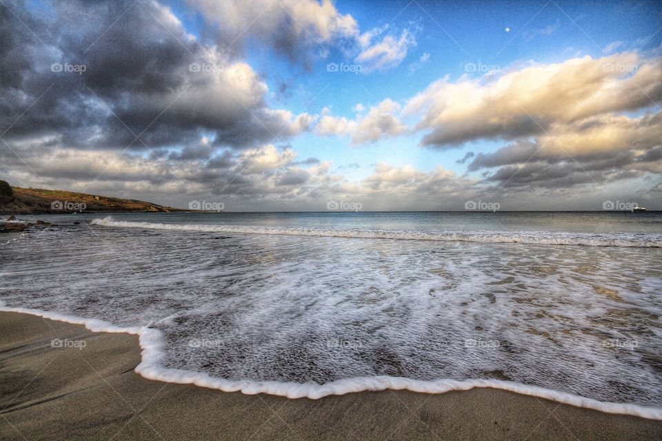 Frothy Waves. A wave froths on a sandy beach in Cornwall.