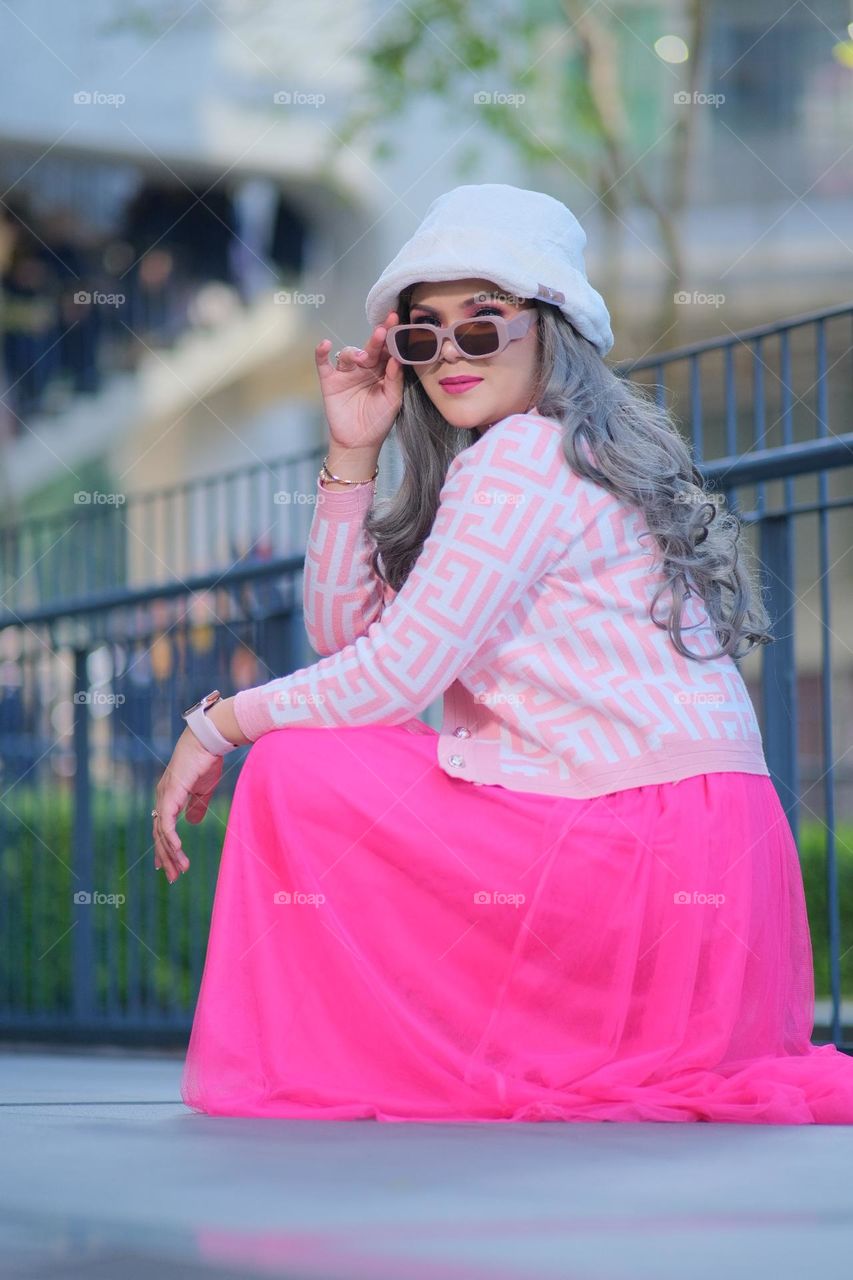 A woman wearing a pink skirt looks like a Barbie doll with blonde long hair. Fashionable concept photography.