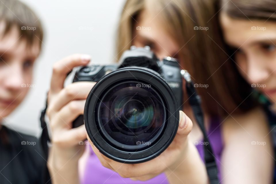 Young people are studying a SLR camera close-up of a blurred background.
