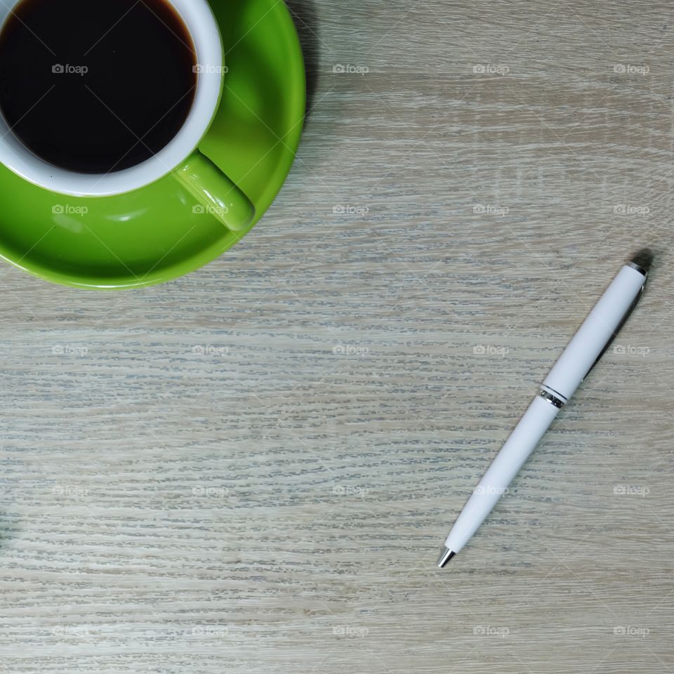 Coffee in green cup and pen