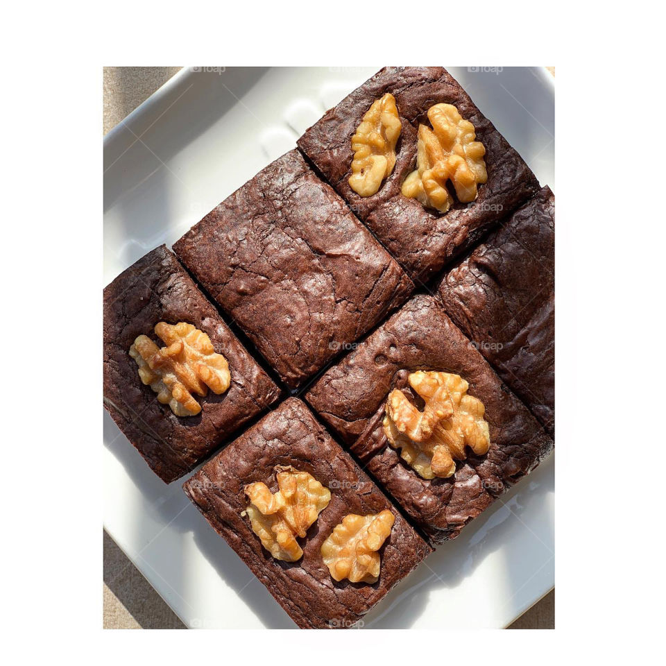 Plain original brownies and walnut brownies put together on white glass plate in flatlay 