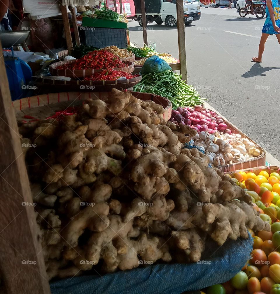 ASSORTED VEGETABLES LIKE GINGER, TOMATOES π
, GARLIC , RED ONION, BEANS π±, RED CHILI πΆοΈ, ONION STRING , ARE DISPLAYED FOR SALE AT A PUBLIC MARKET,