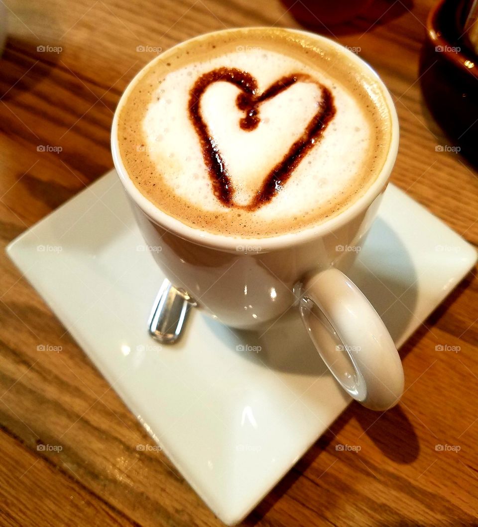 Warm cup of mocha coffee made with a cute chocolate heart in the frothy foam!