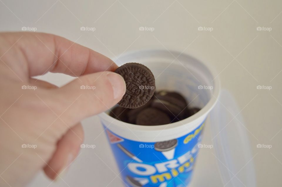 Persons hand taking a Oreo mini from an open go pack container 