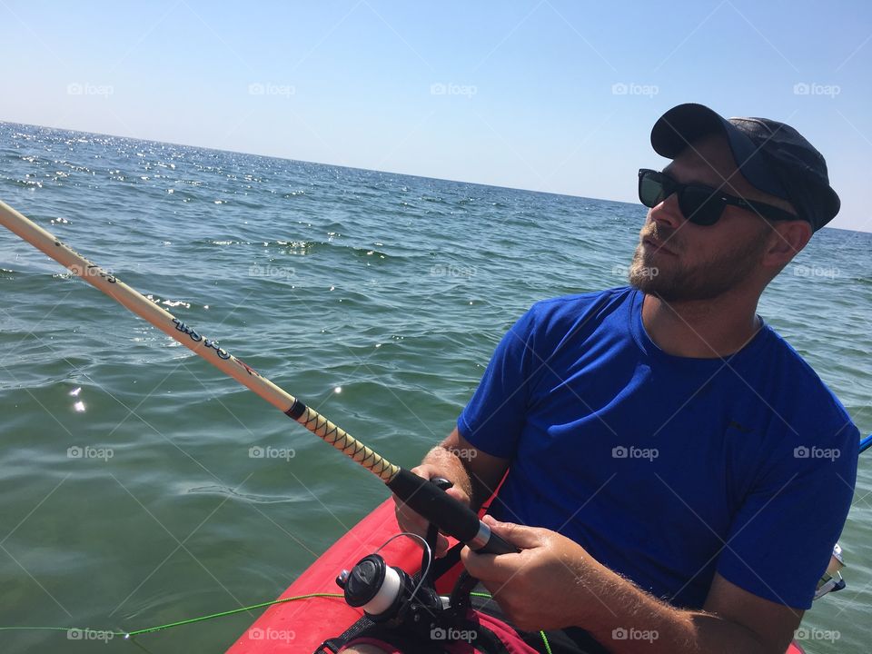 Man reeling his fishing rod while fishing in ocean from kayak