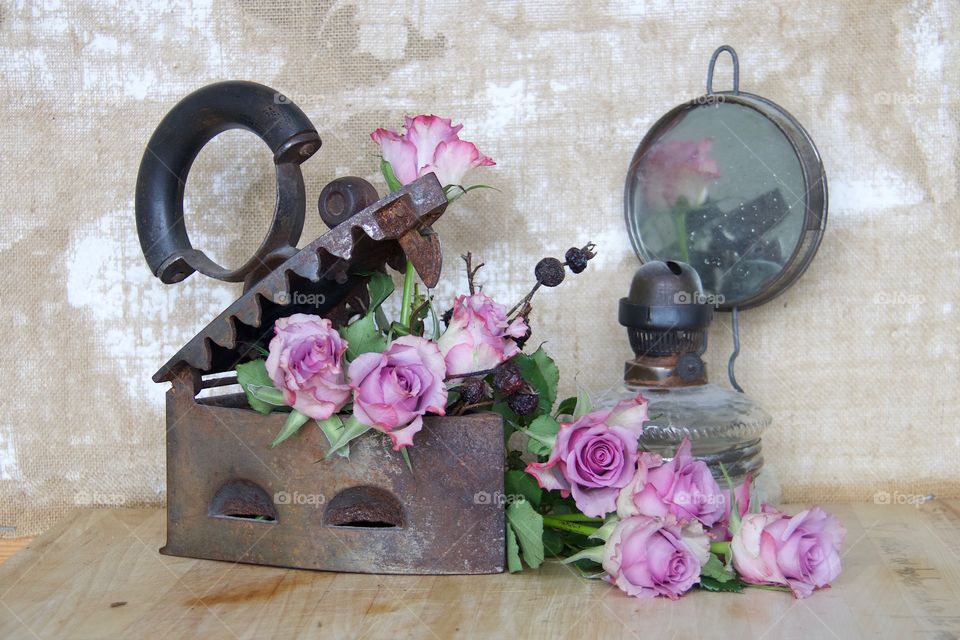 Pink roses in a iron and an old oil lamp