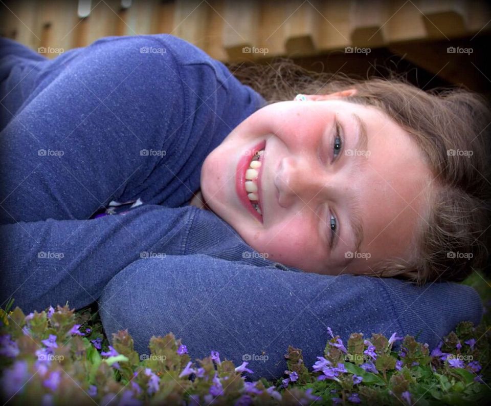 My beautiful nine-year-old daughter laying in a patch of pretty, purple flowers. 