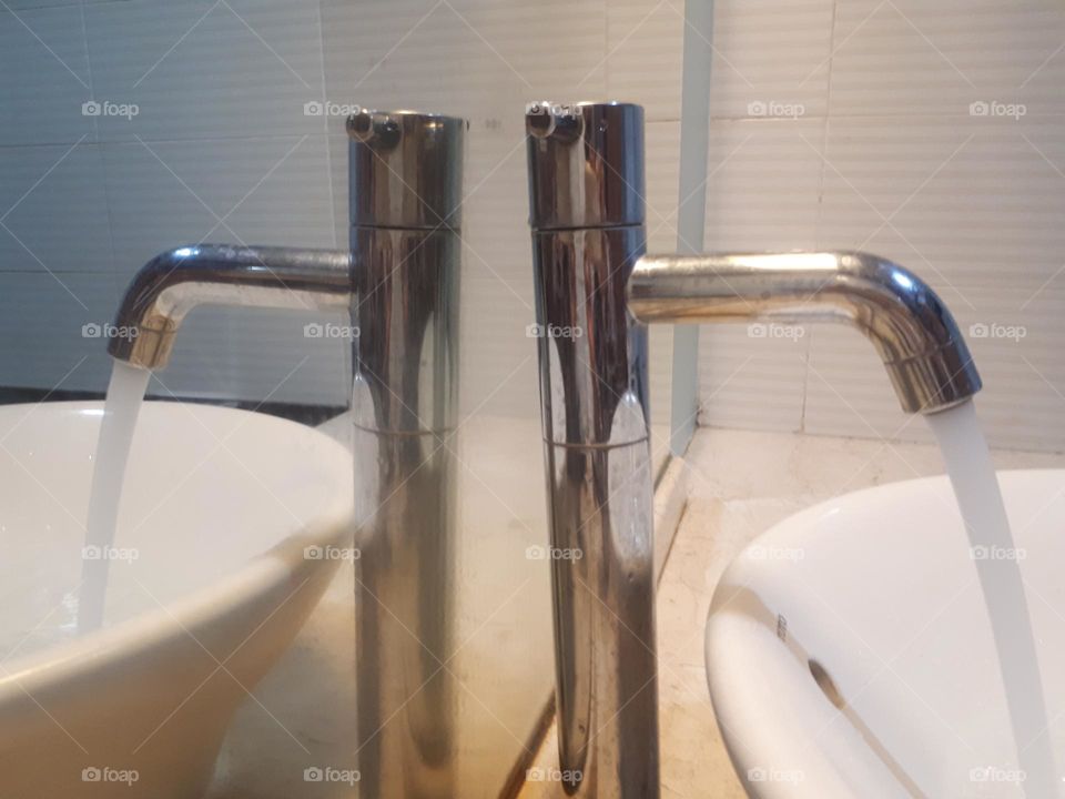 The sink made of stainless steel is reflected by the mirror in the bathroom in the hotel