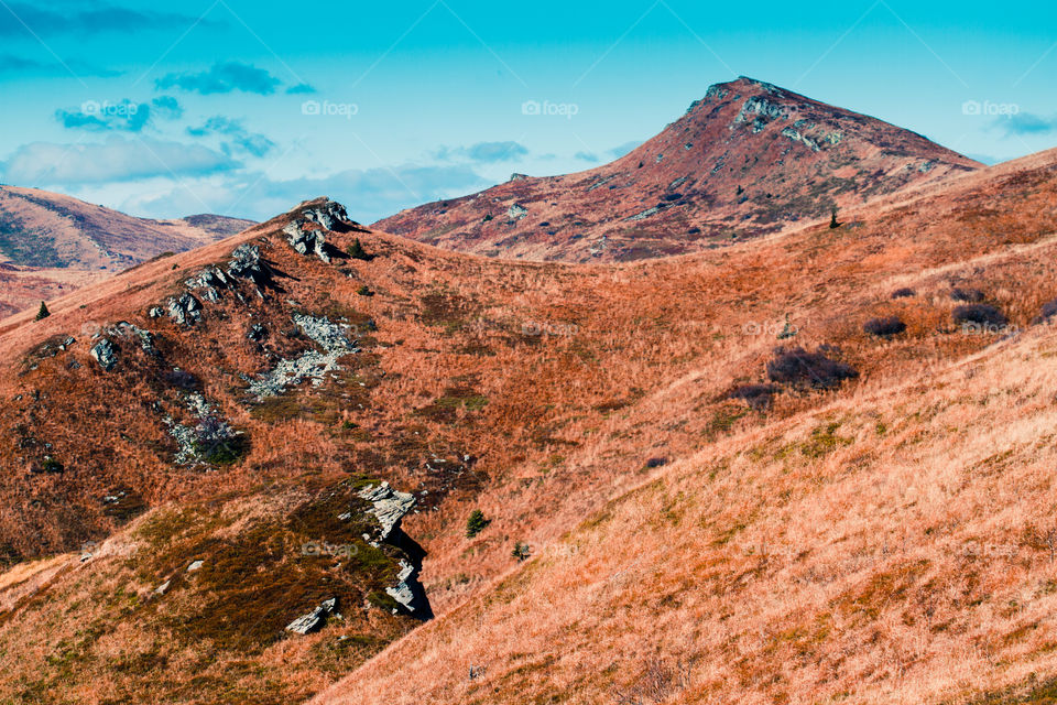 Autumn in The Bieszczady Mountains in Poland. Hillsides coloured with yellow, red, brown. Fall scenery, mountain landscape view from distance