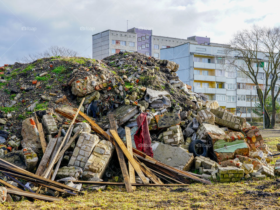 heap of rubble after demolition of an old house, suburban block of flats background