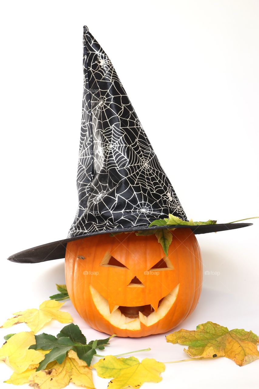 A pumpkin in a hat for Halloween and leaves 