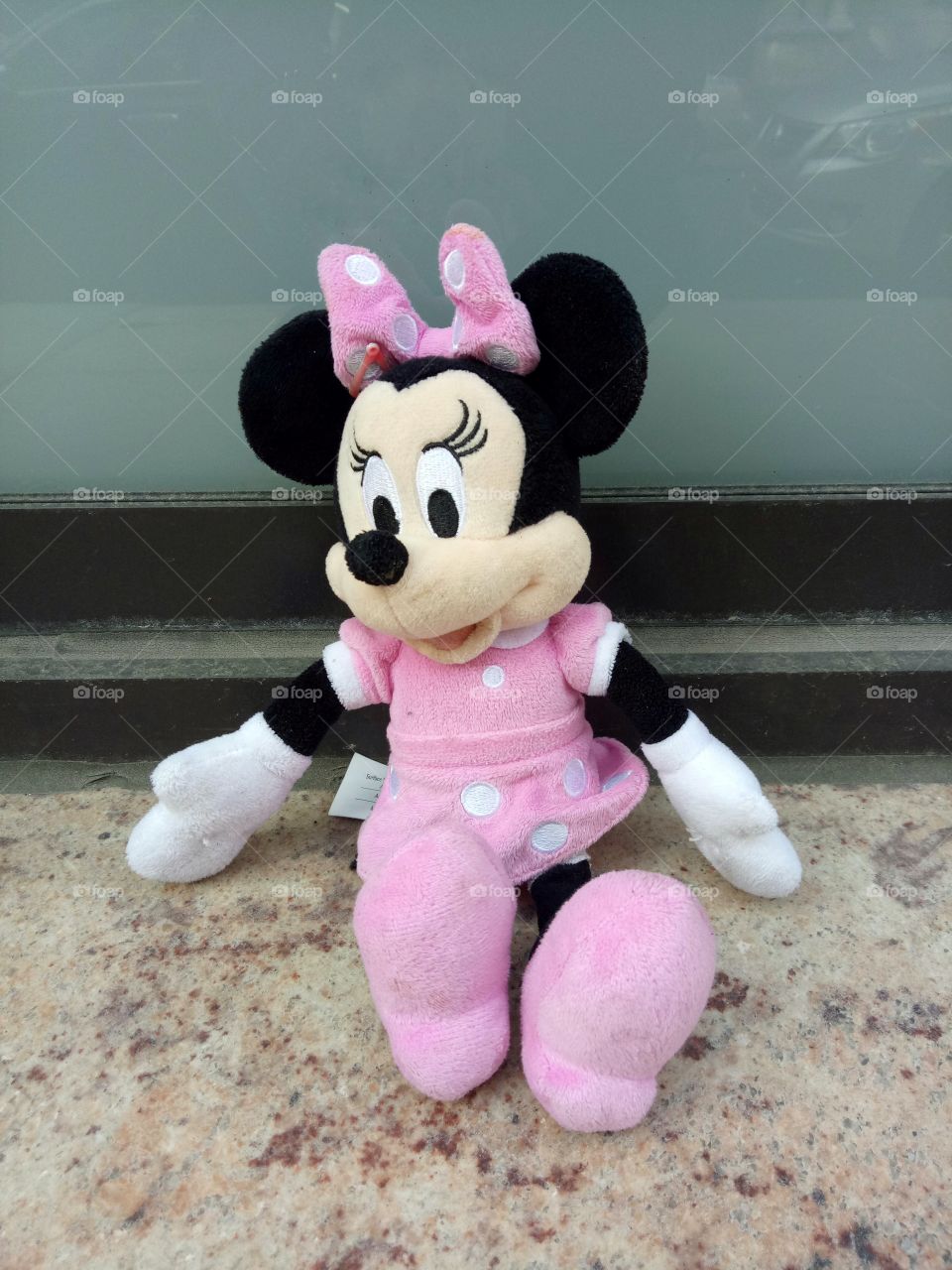 Minnie mouse sitting and leaning outside the building with cute pink attire. Waiting for her brother Micky mouse.