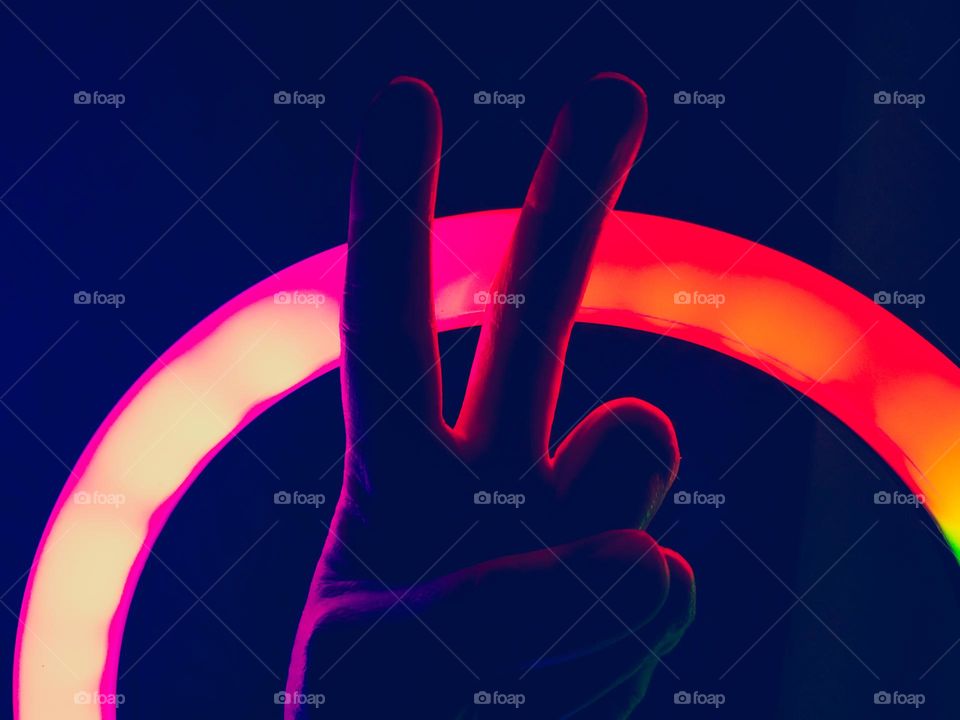 Colorful illuminated silhouette of a hand making the peace symbol.