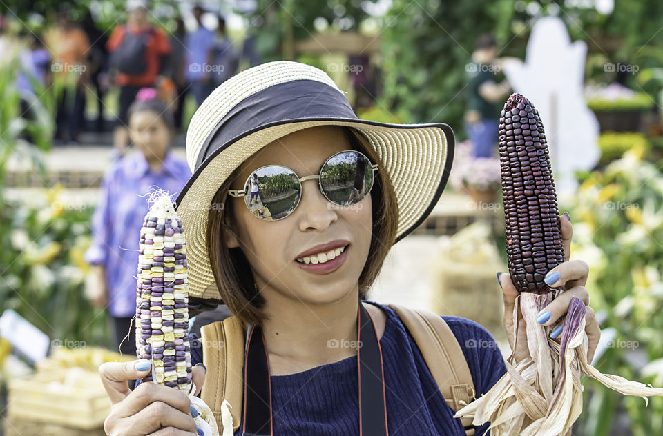 A woman holding the corn at the show in the farm.