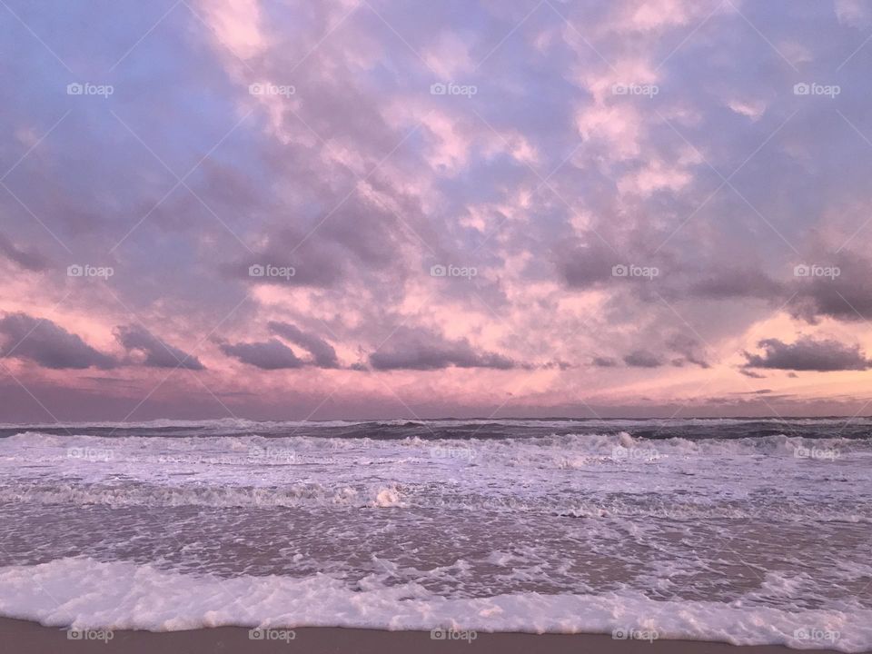 Pink clouds sunset over waves