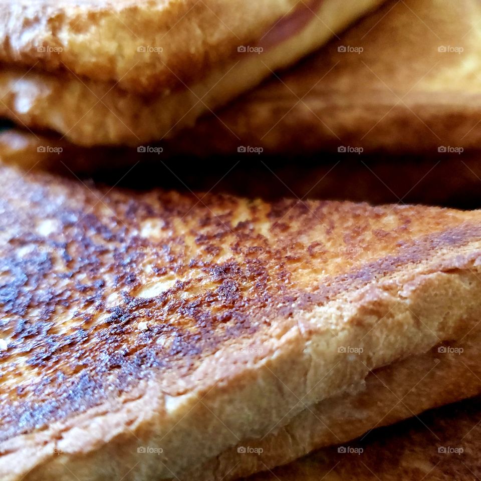 Closeup texture of a hot delicious fried ham and cheese sandwich.