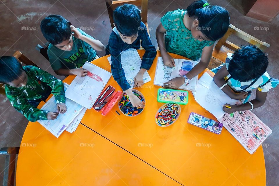 Kids doing activities on yellow color table