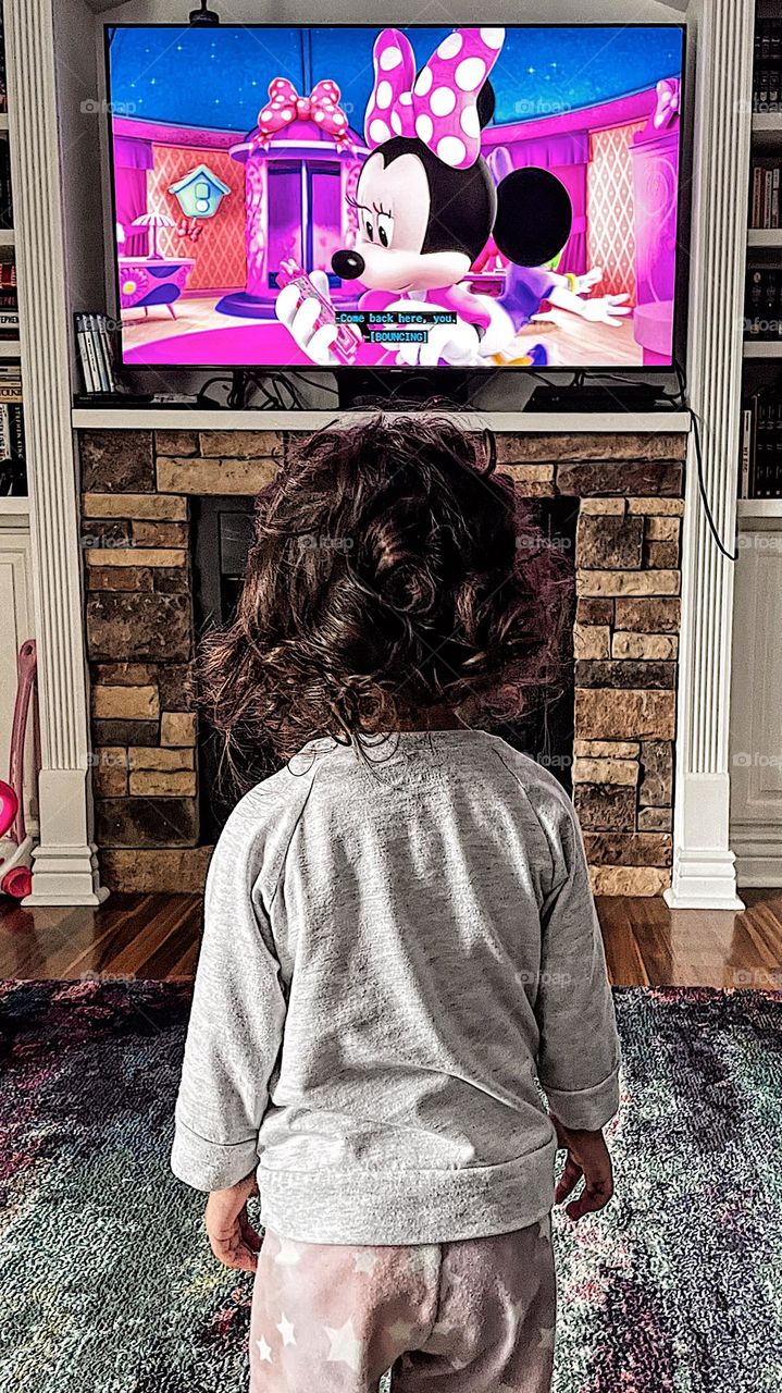 Toddler watching Minnie Mouse, toddler watches Disney, Disney channel on flat screen TV, large television with Minnie Mouse playing, little girl watches Mickey Mouse show, watching cartoons in the morning, cartoons playing on Saturday morning 