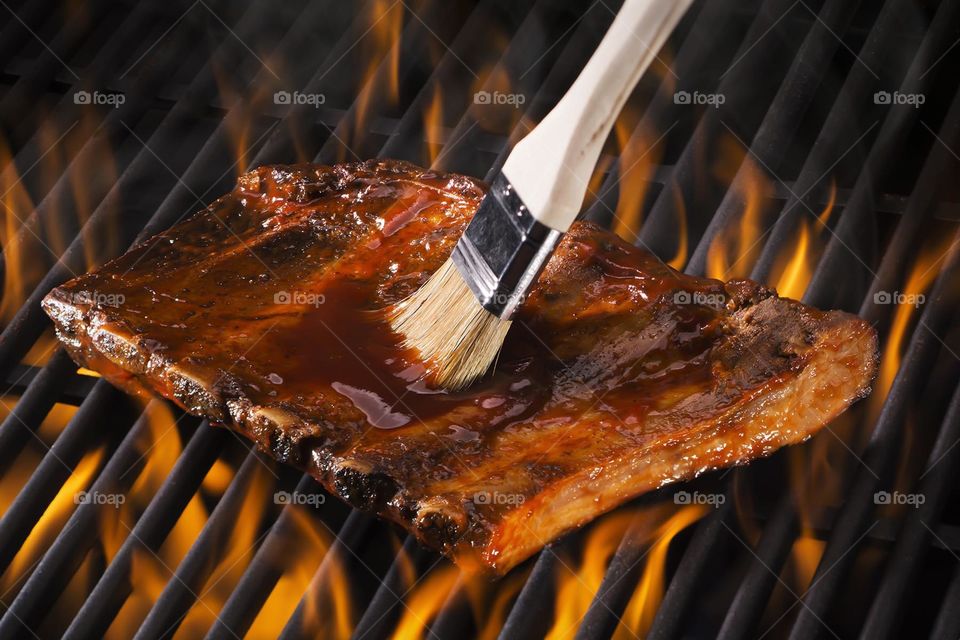Ribs grilling on a flaming barbecue 