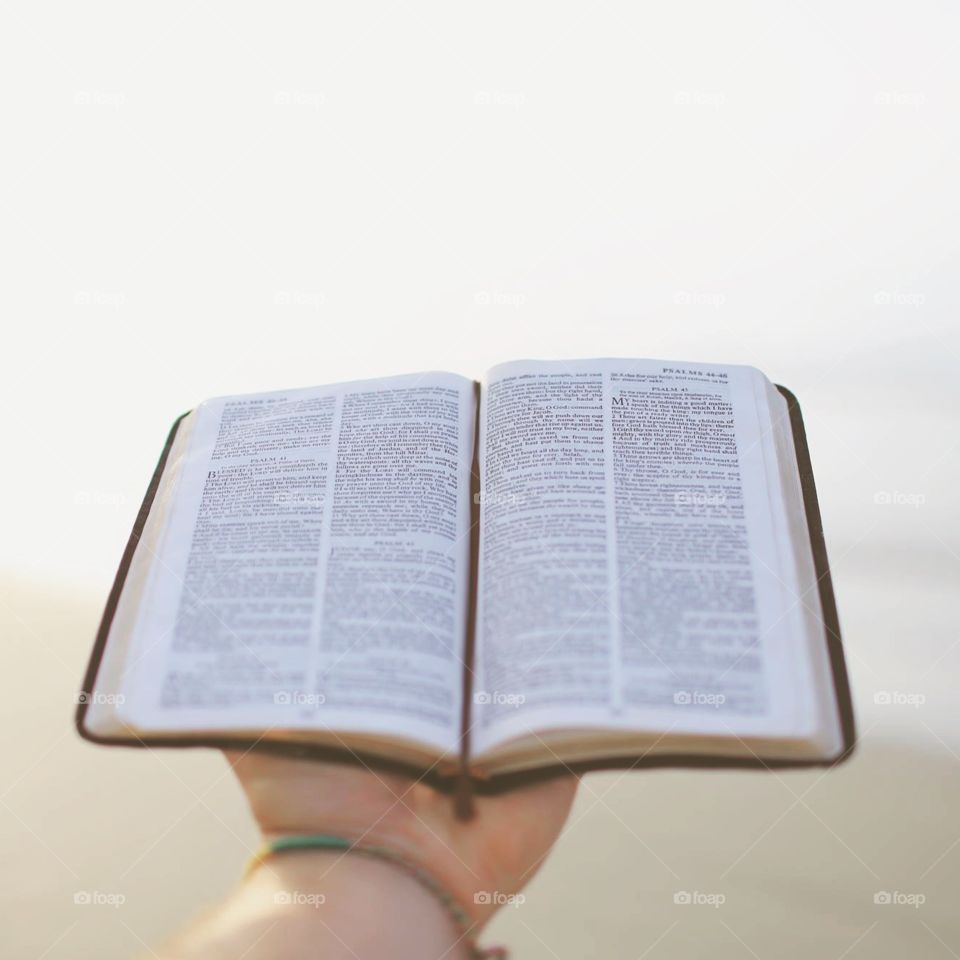 Holding a Bible. Holding a Bible on the beach in the morning.