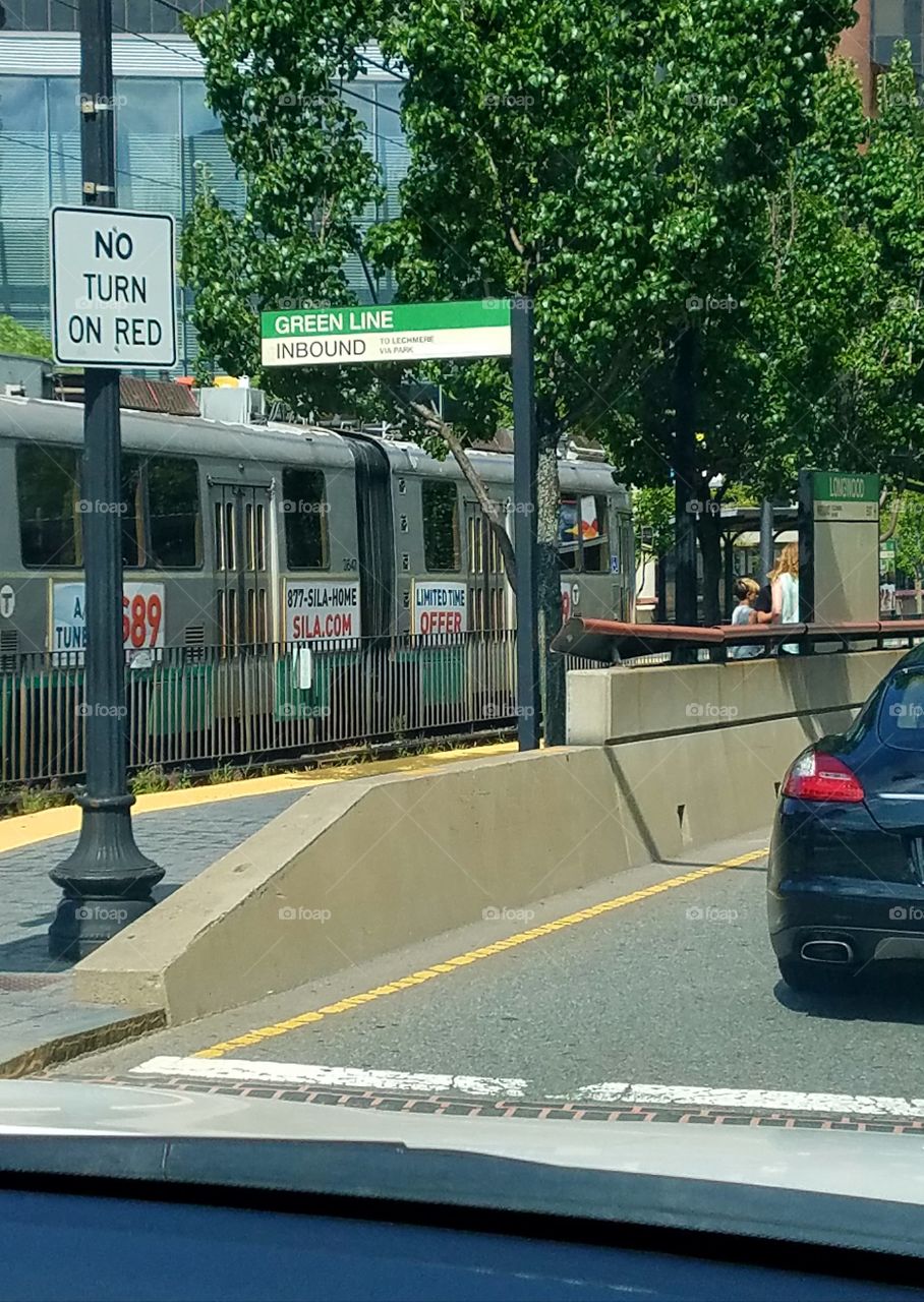 Boston Subway running above ground on main street, along side driving road.