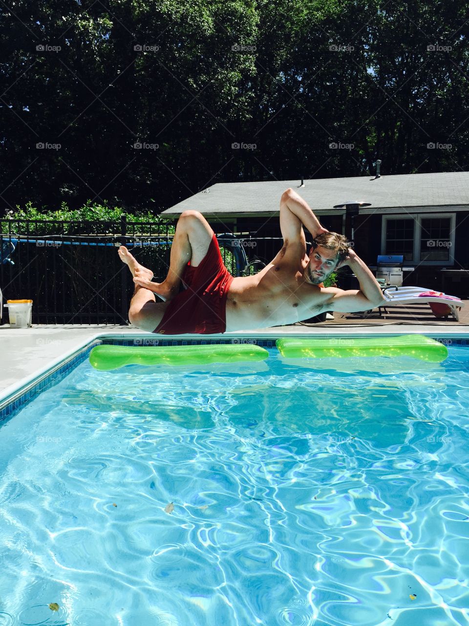 Young man jumping into swimming pool