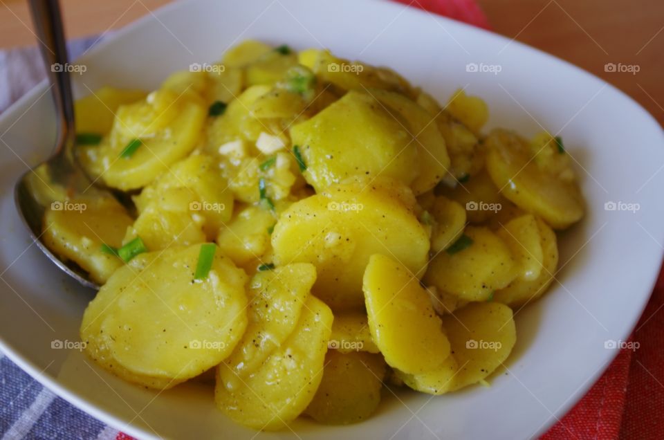 tasty potato salad on white plate with silver spoon