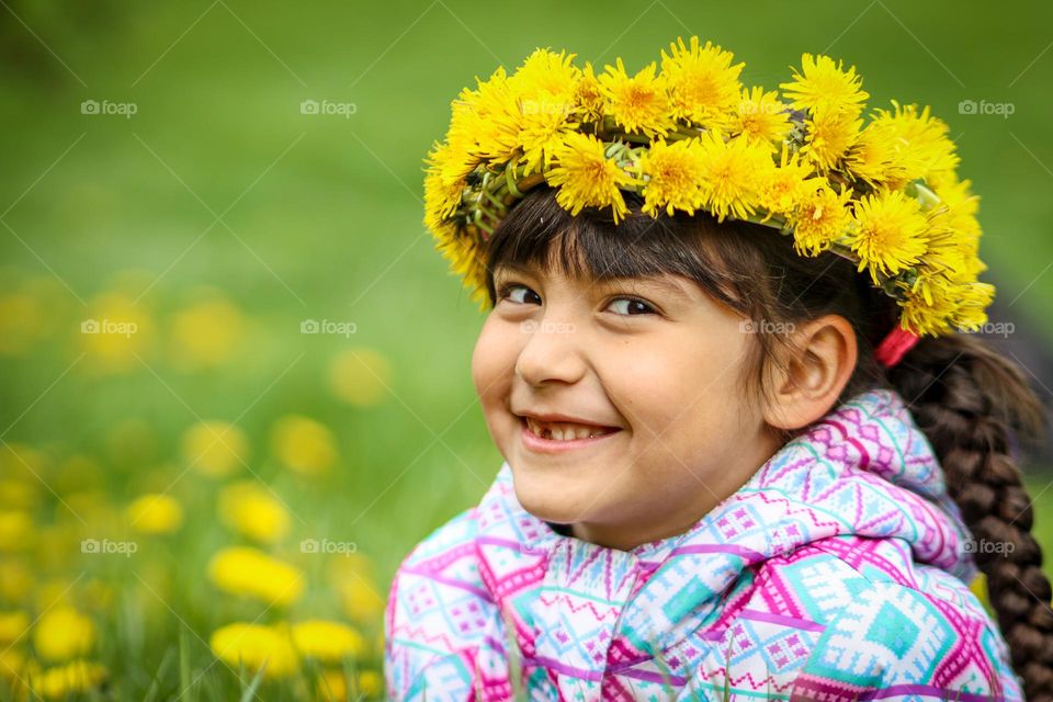 Cute little girl in a dandelion wreath