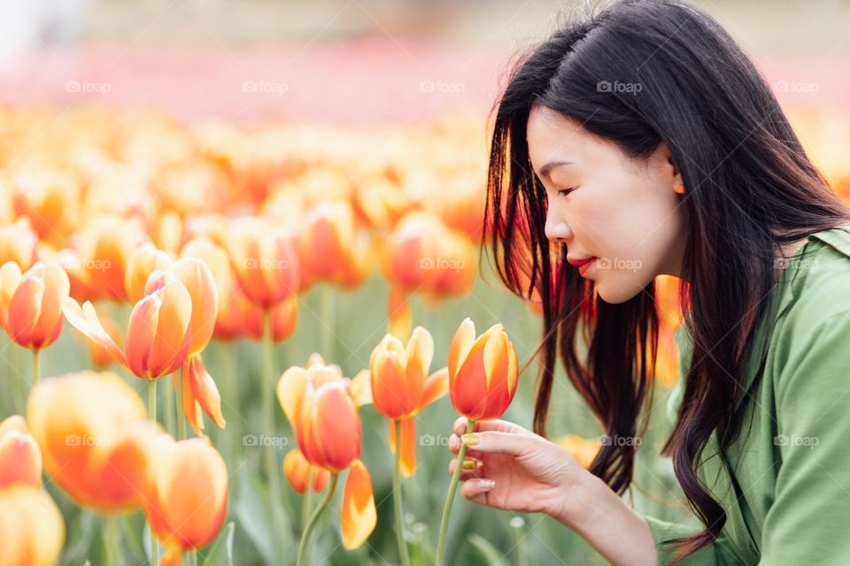 Beautiful Asian woman sniffing tulips 