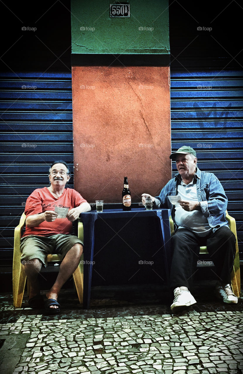 The old friends. . Two guys enjoying some beer at night. 