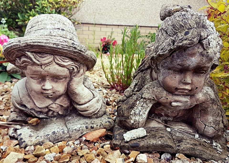 Old statues of a boy and a girl in a garden