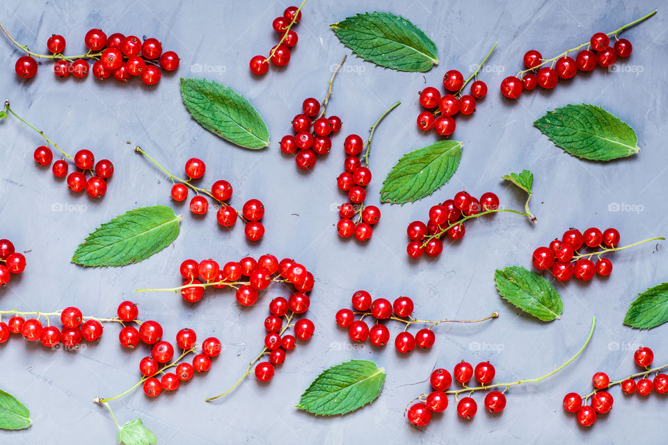 Fresh red currant, mint leaves on gray background 