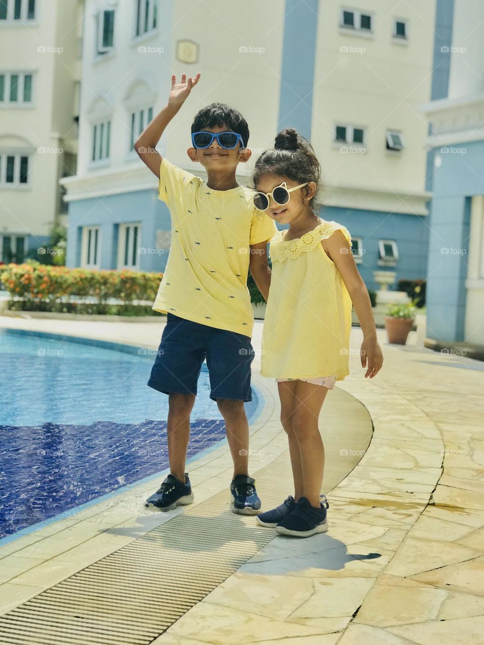 A baby girl and boy stands near the swimming pool in summer season and enjoying a lot 😍