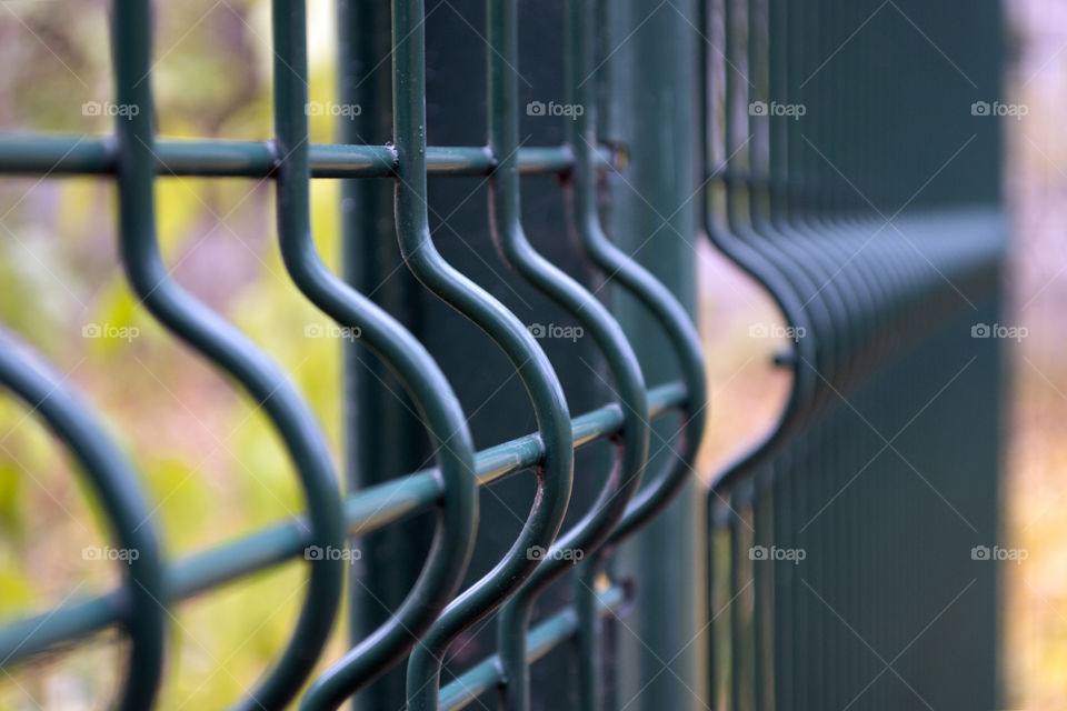 Details of a large dark green metal fence