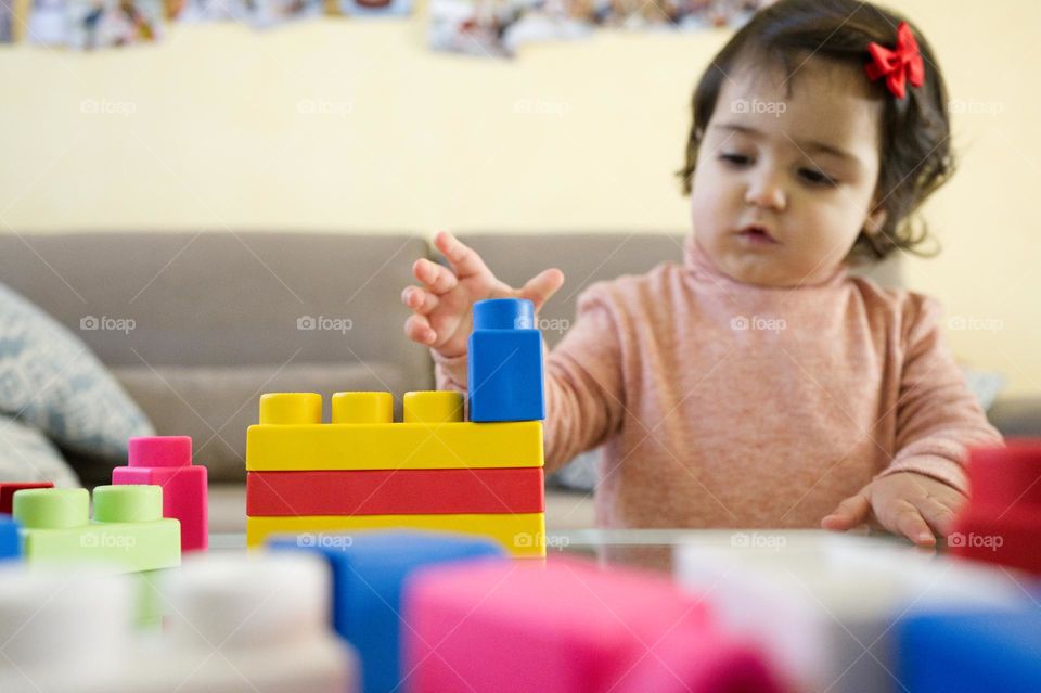 little girl playing rectangular colored constructions