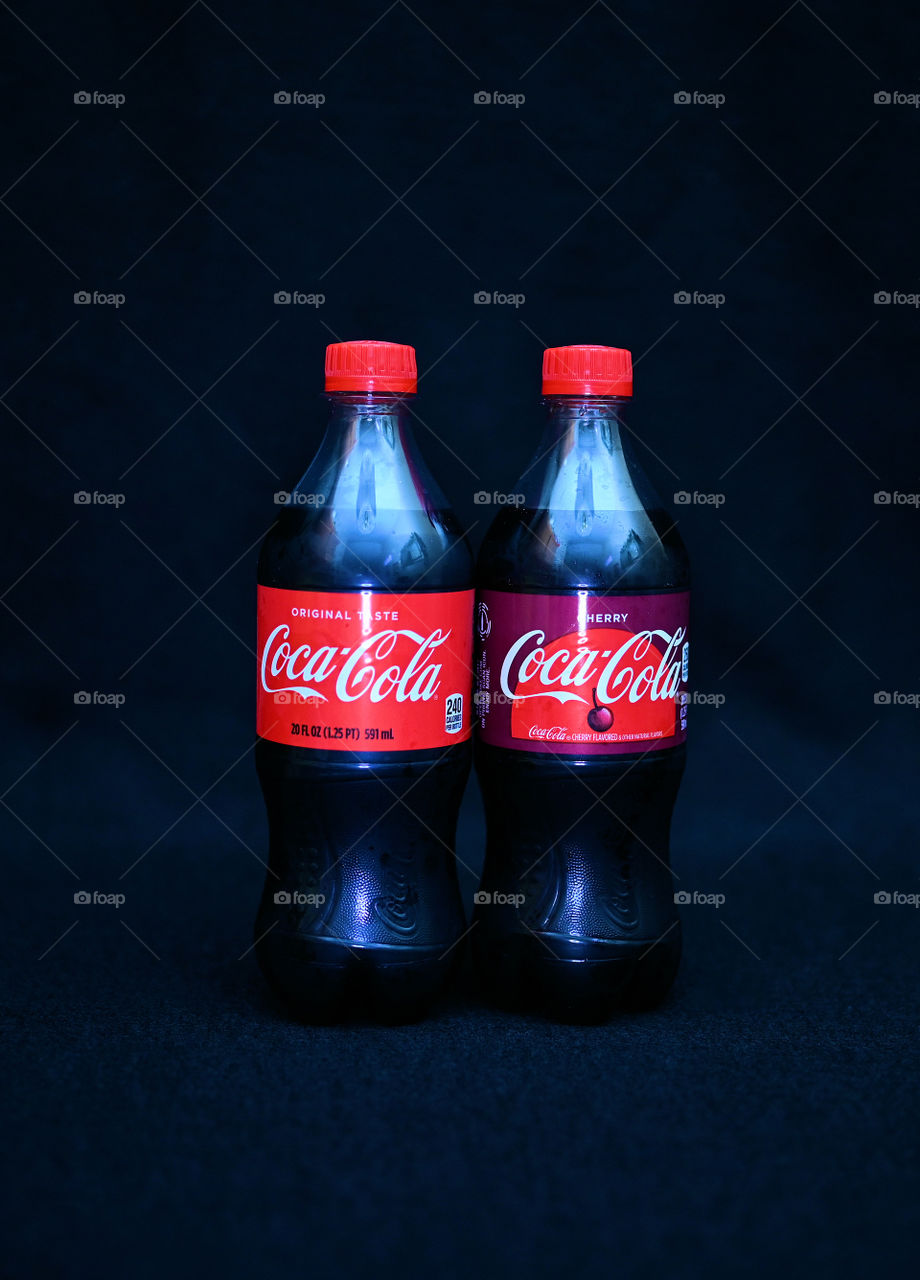 Close up shot of two Coca Cola with black background with the mists at the studio.