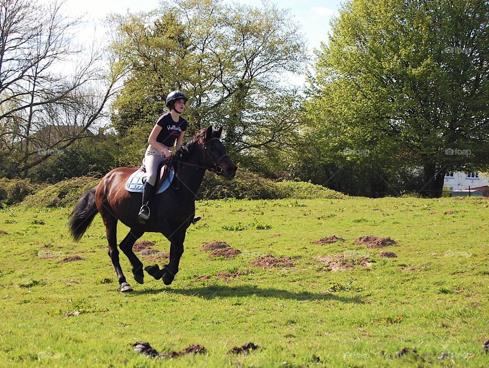 A girl and her pretty mare galloping in a huge field, in summer 